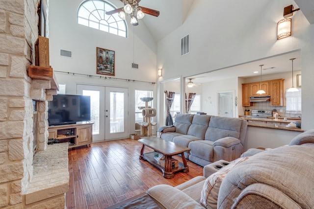 living room with a wealth of natural light, light hardwood / wood-style floors, french doors, and ceiling fan