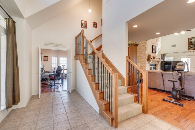 staircase with tile patterned floors and high vaulted ceiling