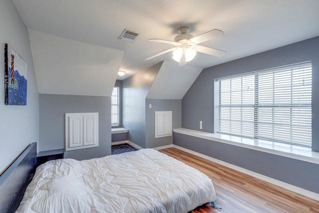 bedroom with multiple windows, wood-type flooring, lofted ceiling, and ceiling fan