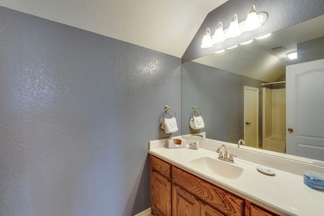 bathroom featuring lofted ceiling, vanity, and a shower