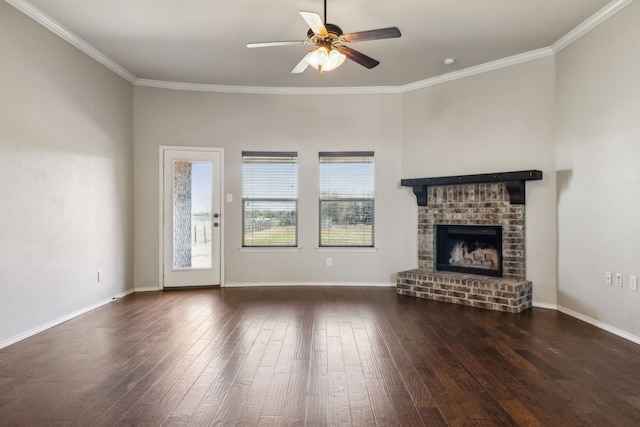 unfurnished living room featuring a brick fireplace, crown molding, dark wood-type flooring, and ceiling fan