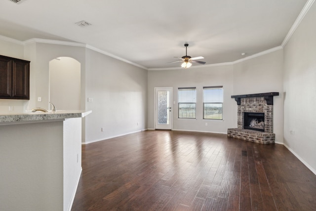 unfurnished living room featuring ceiling fan, a fireplace, dark hardwood / wood-style flooring, and crown molding