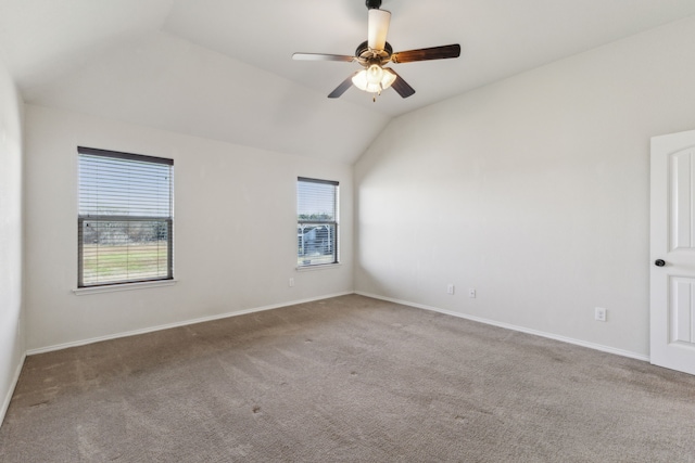 carpeted spare room featuring vaulted ceiling and ceiling fan