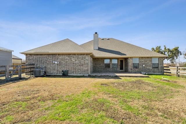 rear view of house featuring a yard, central air condition unit, and a patio area