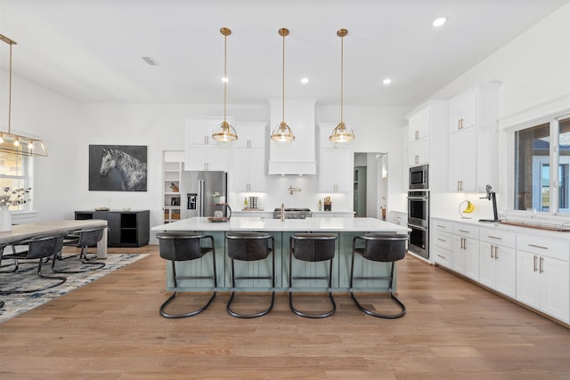 kitchen with stainless steel appliances, a breakfast bar, pendant lighting, and a large island with sink