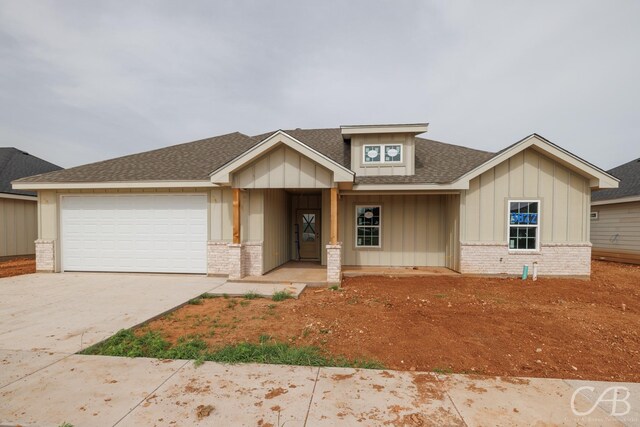 3822 National Dr, Abilene, TX 79602 - view of front facade with brick siding, driveway, board and batten siding, a garage, and roof with shingles