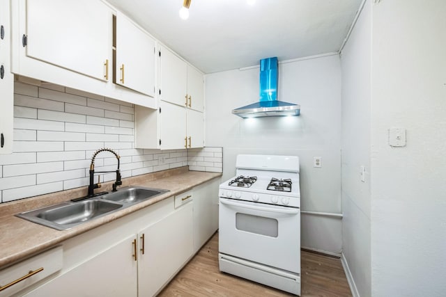 kitchen featuring wall chimney exhaust hood, sink, white gas stove, white cabinets, and backsplash