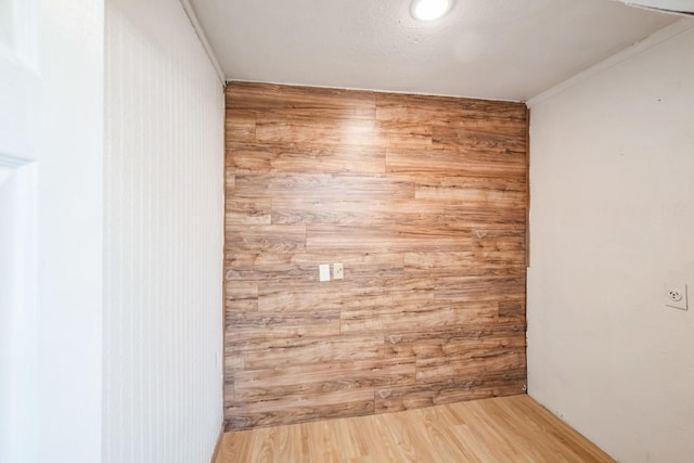 spare room with crown molding, hardwood / wood-style floors, and wood walls