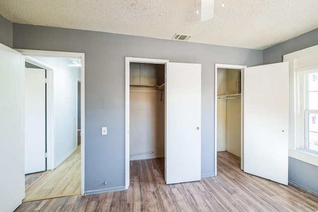 unfurnished bedroom featuring light hardwood / wood-style floors, multiple windows, and a textured ceiling