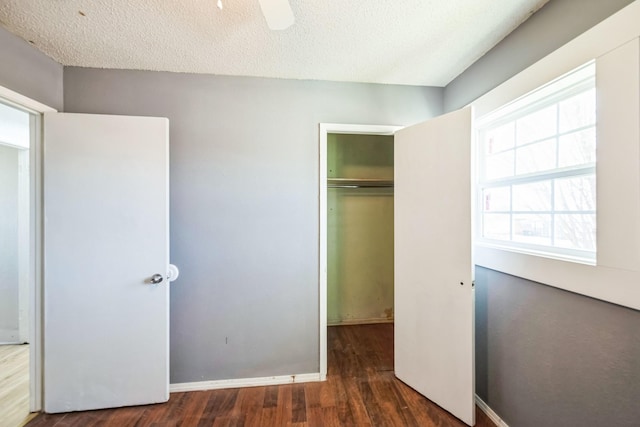 unfurnished bedroom featuring ceiling fan, dark hardwood / wood-style floors, a textured ceiling, and a closet