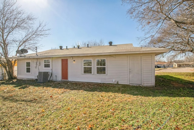 rear view of house featuring central AC unit and a lawn