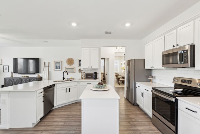 kitchen featuring sink, stainless steel appliances, white cabinets, and a kitchen island