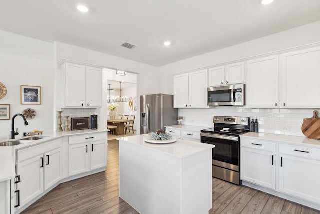 kitchen with sink, appliances with stainless steel finishes, light hardwood / wood-style floors, white cabinets, and decorative backsplash