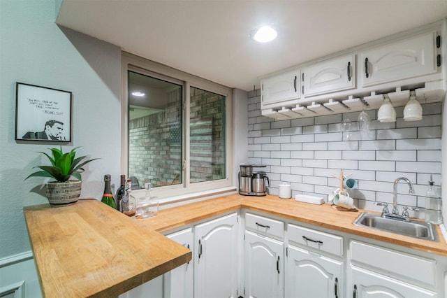 kitchen featuring sink, butcher block countertops, decorative backsplash, and white cabinets