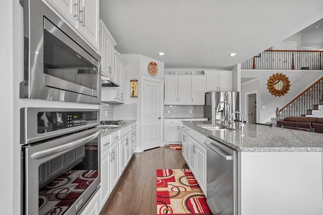 kitchen featuring appliances with stainless steel finishes, a center island with sink, and white cabinets