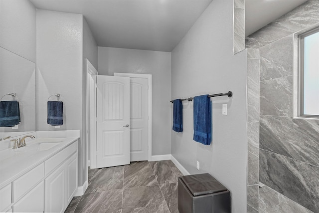 bathroom with tiled shower and vanity