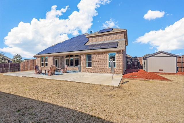 back of property with a lawn, a shed, a patio, and solar panels