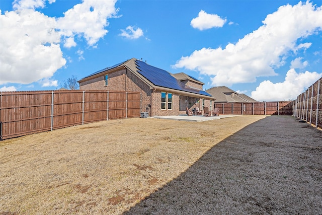 rear view of house featuring a lawn, a patio area, and solar panels