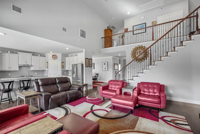 living room with sink, dark hardwood / wood-style flooring, and a towering ceiling