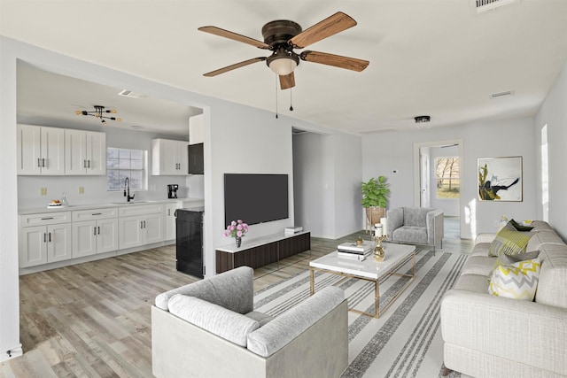 living room featuring sink, ceiling fan, and light wood-type flooring