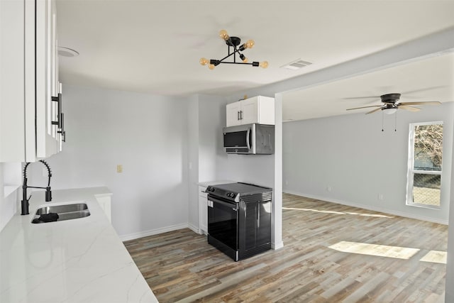 kitchen featuring sink, hardwood / wood-style flooring, black range with electric stovetop, light stone countertops, and white cabinets