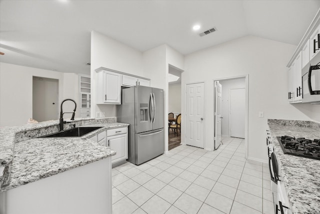 kitchen featuring lofted ceiling, sink, light stone counters, stainless steel appliances, and white cabinets