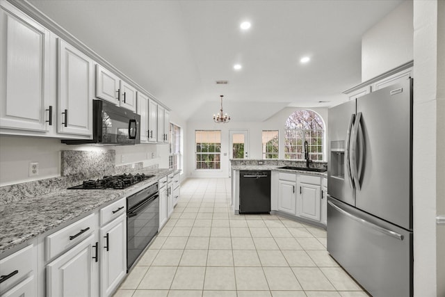 kitchen with sink, white cabinetry, light stone counters, hanging light fixtures, and black appliances