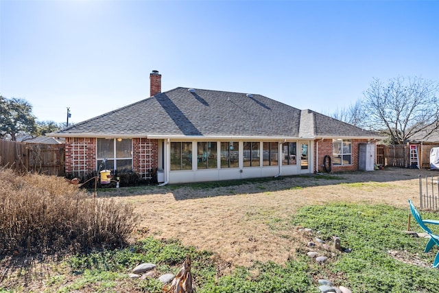 back of property featuring a sunroom and a lawn