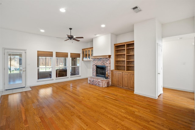 unfurnished living room featuring ceiling fan, a fireplace, and light wood-type flooring