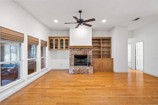 unfurnished living room featuring ceiling fan, a brick fireplace, and light hardwood / wood-style floors