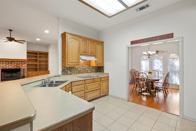 kitchen with sink, hanging light fixtures, light tile patterned floors, kitchen peninsula, and backsplash