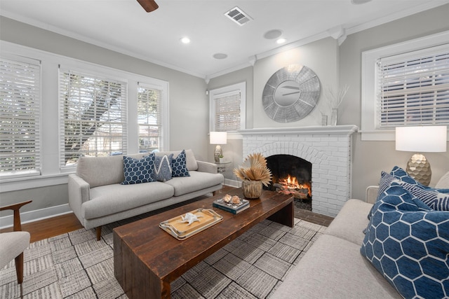 living room featuring a brick fireplace, crown molding, hardwood / wood-style floors, and ceiling fan