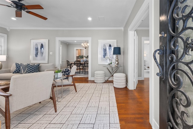 living room with ceiling fan with notable chandelier, ornamental molding, and light hardwood / wood-style floors