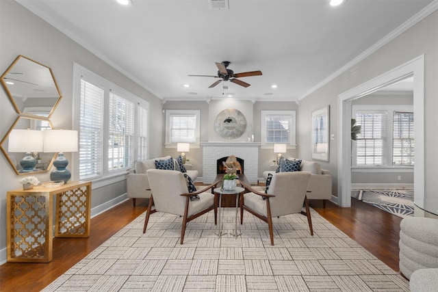 living room featuring ornamental molding, a brick fireplace, ceiling fan, and light hardwood / wood-style floors