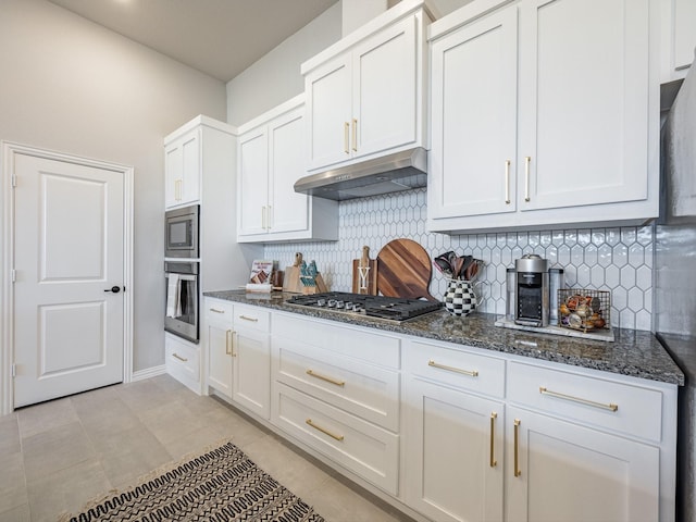 kitchen featuring white cabinetry, tasteful backsplash, stainless steel appliances, and dark stone countertops