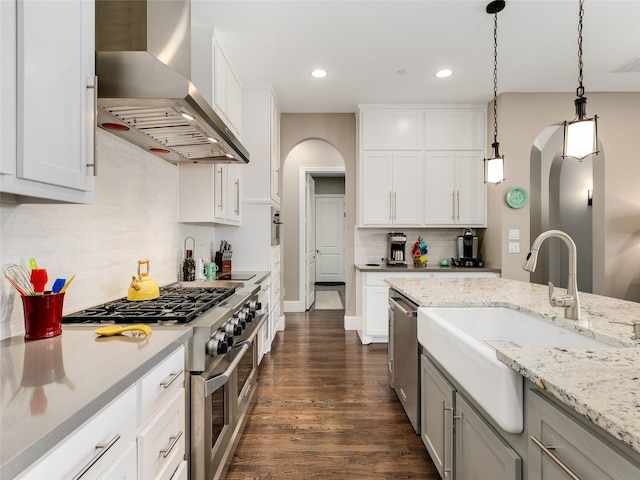 kitchen featuring extractor fan, white cabinetry, sink, hanging light fixtures, and stainless steel appliances