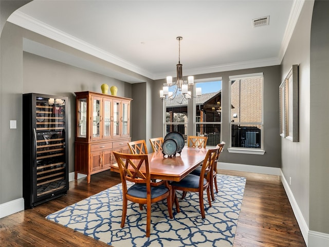 dining space featuring ornamental molding, a chandelier, beverage cooler, and dark hardwood / wood-style flooring