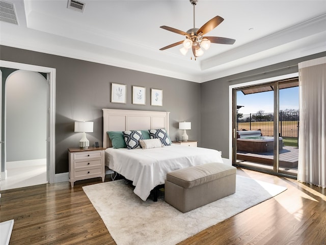 bedroom with dark hardwood / wood-style flooring, access to exterior, a tray ceiling, and ceiling fan