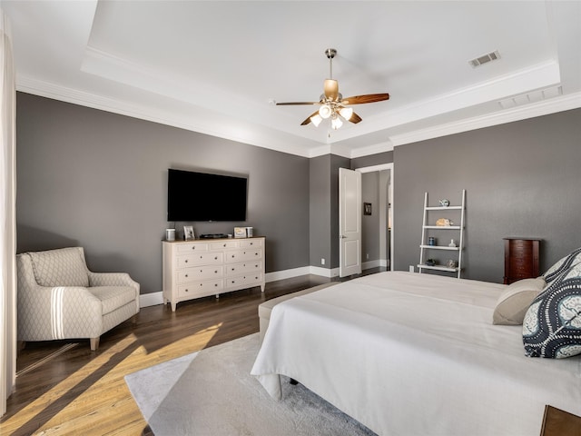 bedroom featuring dark wood-type flooring, ceiling fan, crown molding, and a raised ceiling