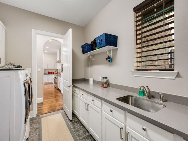 kitchen featuring sink, washer and clothes dryer, high end range, white cabinets, and dark hardwood / wood-style flooring