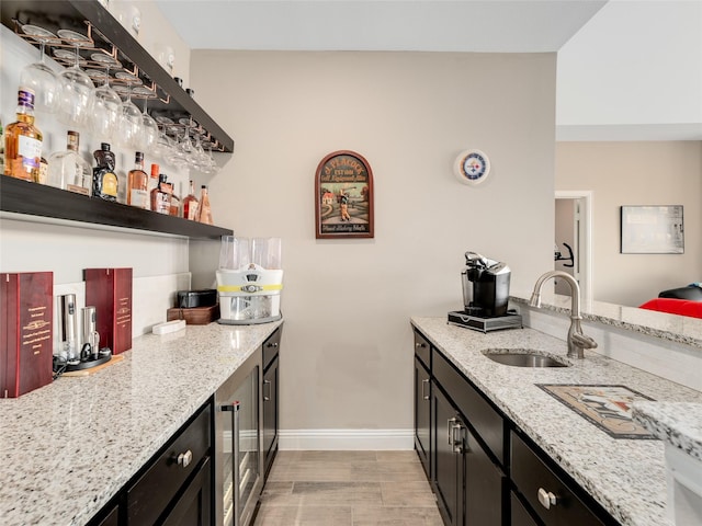 kitchen featuring sink, beverage cooler, and light stone counters