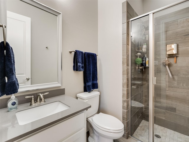 bathroom featuring vanity, toilet, and a shower with shower door