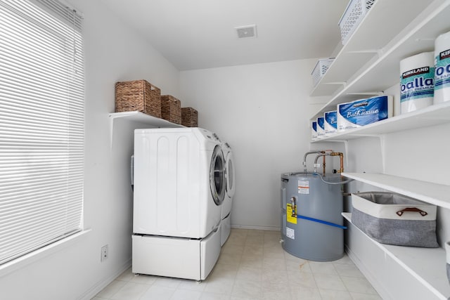 laundry room featuring washing machine and dryer, electric water heater, and a wealth of natural light