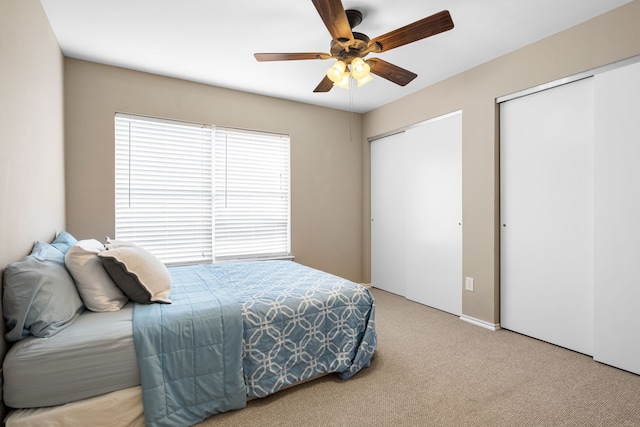 bedroom with multiple closets, light carpet, and ceiling fan