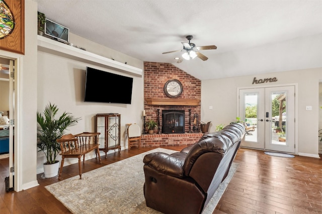 living room featuring ceiling fan, dark hardwood / wood-style floors, a fireplace, vaulted ceiling, and french doors