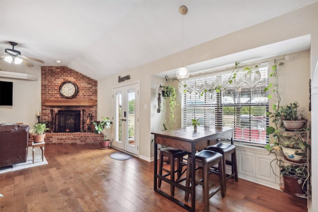 dining space with lofted ceiling, dark wood-type flooring, a fireplace, and french doors