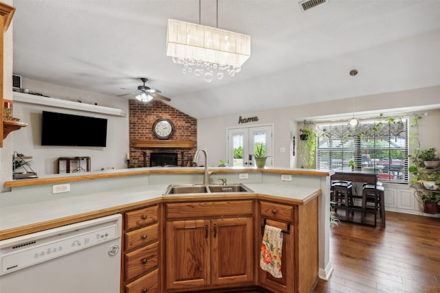 kitchen with lofted ceiling, sink, a brick fireplace, dishwasher, and pendant lighting