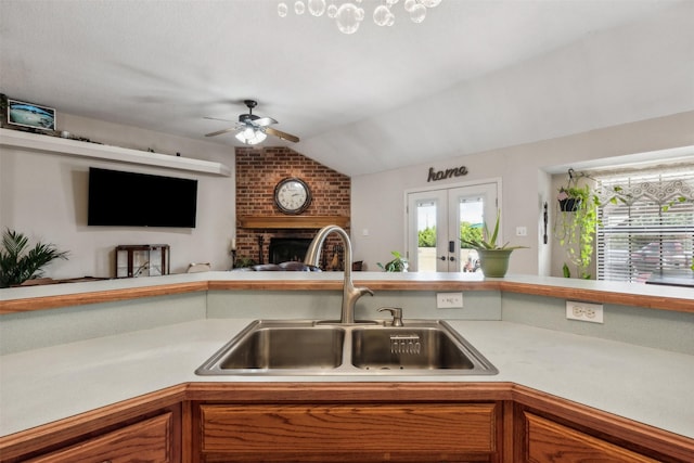 kitchen with french doors, lofted ceiling, sink, a brick fireplace, and ceiling fan