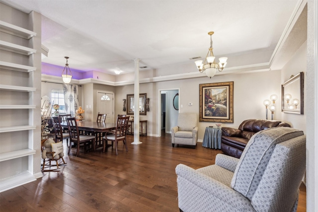 living room with an inviting chandelier, dark hardwood / wood-style flooring, and decorative columns