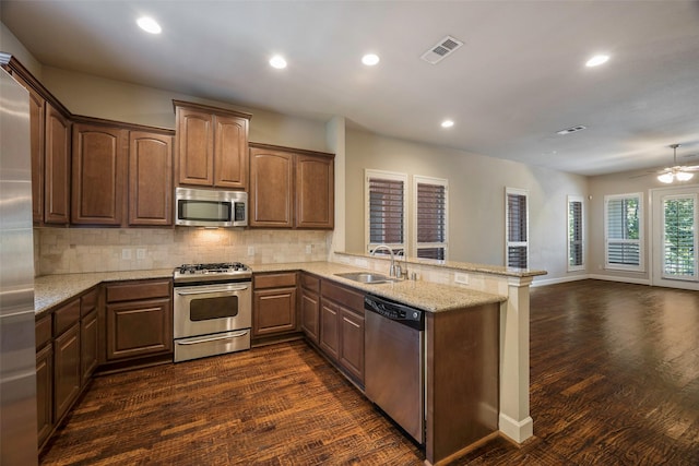 kitchen featuring sink, stainless steel appliances, kitchen peninsula, and light stone countertops